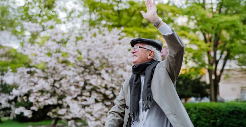 Aktiver Senior winkt froehlich im Park